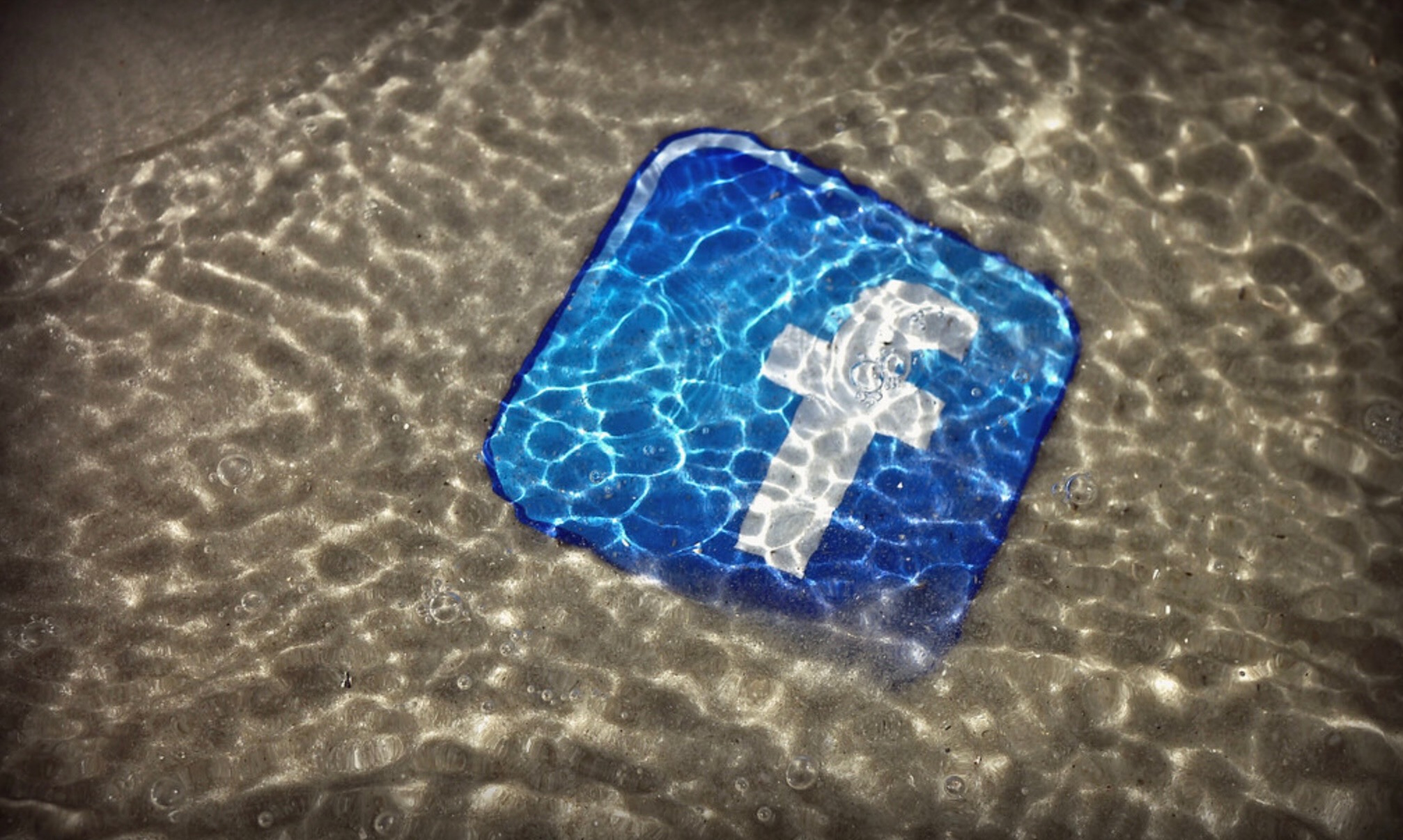 Tile with Facebook logo submerged in water for Ronnie Stangler MD good reads page regarding Clicking Accept is not Informed Consent.