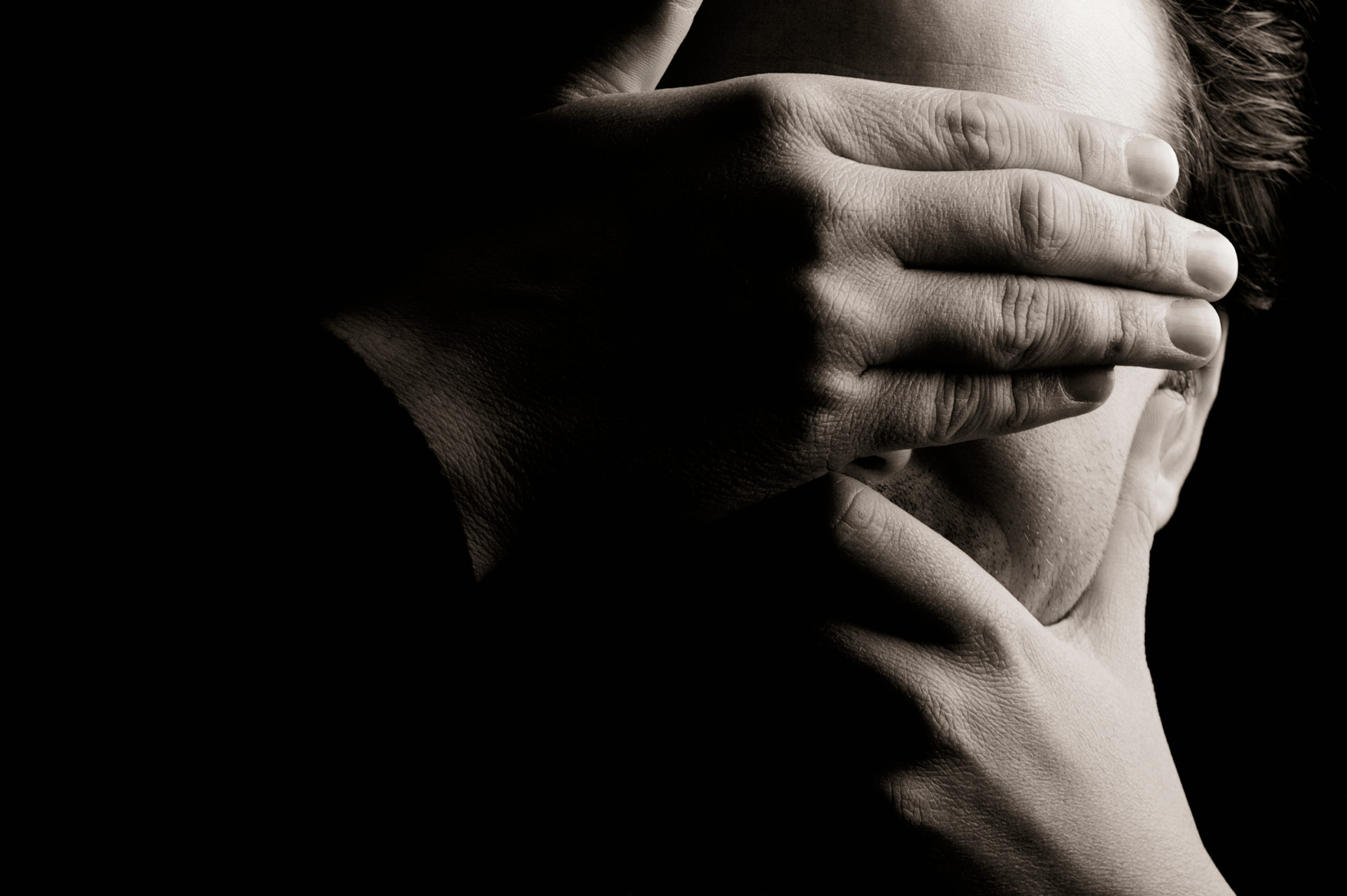 Photograph of young man with hands covering his face on Ronnie Stangler MD Good Reads page regarding What Causes Procrastination and How to Face it.